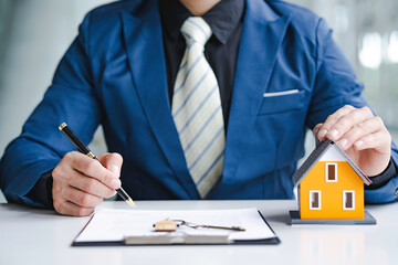 Man Signing A Contract When Buying A New House after agreeing to make a home purchase agreement and make a loan agreement. Discussion with a real estate agent