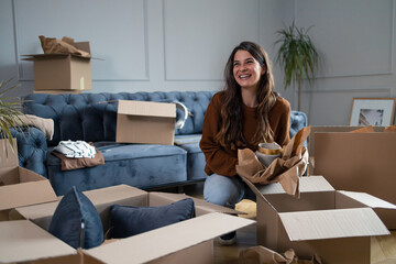 Happy woman enjoying while unpacking boxes in her new home.
