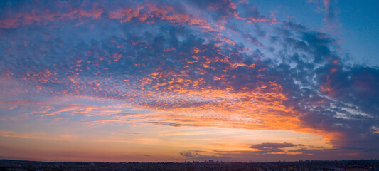 Fototapeta na wymiar End of the day with a sky between clouds and very colorful, highlighting blue and orange. At the base of the image, and in the background, is the silhouette of the city. 