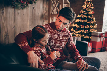 Photo of concerned caring young father cuddle comforting sad daughter wear sweater in decorated...