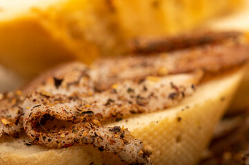 Sliced homemade bacon with pepper and sliced bread, close-up, selective focus.
