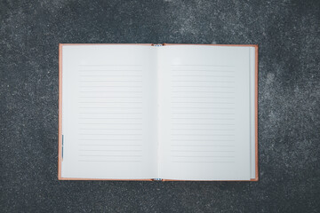 Opened empty notebook with lines on paper on a stone background.