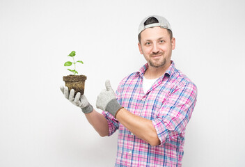 Happy farmer with plant gesturing yes - good job. Plant care concept, isolated on white background....