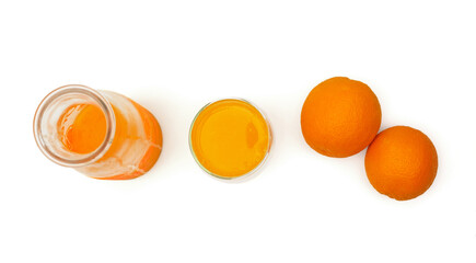Top view of a ripe oranges, glass bottle and mug with fresh squeezed orange juice on white background.
