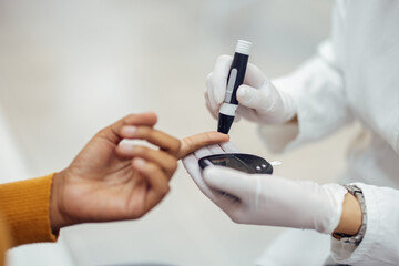 Medical worker using lancing pen and blood glucose meter on patient.Doctor using lancing pen and blood glucose meter for measuring blood sugar level in patient.