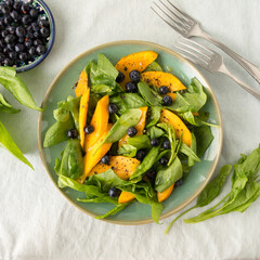 plate with mango, spinach and blueberry salad on the table
