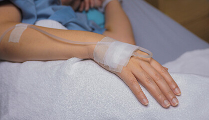 The patient hand with a saline solution on hospital bed.