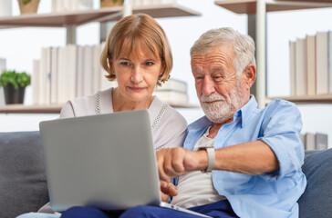 Fototapeta premium Portrait of happy senior couple in living room, Elderly woman and a man using computer laptop on cozy sofa at home, Happy family concepts
