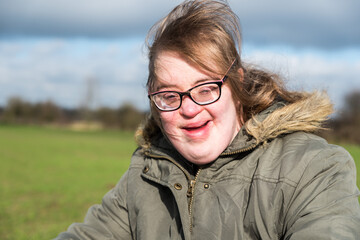 Portrait of a young white woman with Down Syndrome driving a tricycle through the fields