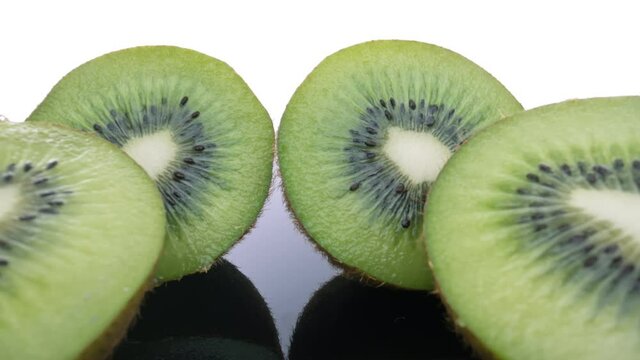 Ripe fresh kiwi, cut in half, on a shiny surface, moving forward to the backside. Extreme macro.