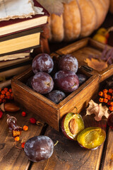 Plums in a wooden box. Two halves of a plum cut in half lie side by side.