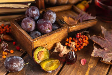 Plums in a wooden box. Two halves of a plum cut in half lie side by side.