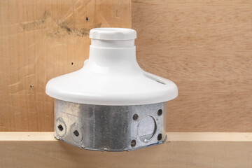 an octagon steel electrical wiring junction box and a white utility light socket in a construction...