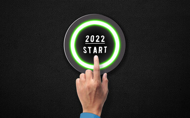 Hand Push Start button 2022 New Year concept. Happy new Year Idea. Human Finger pressing 2022 Start Metal button on Black Metallic Background 