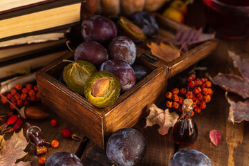 Plums in a wooden box. Two halves of a plum cut in half lie side by side.