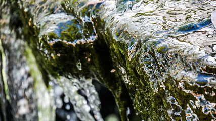 Close up detail of waterfall flowing over rocks in the forest.