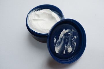 A white skin moisturizing cream in a blue container on a white background.