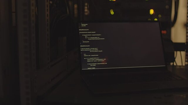 Locked-down of portable computer in dark room, computer code program running on screen