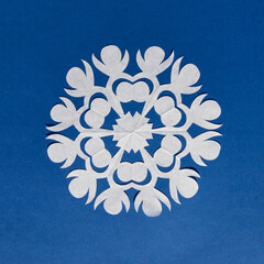 White paper snowflake on a blue background, handmade new year decoration
