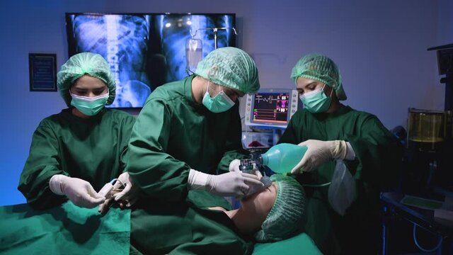 Professional surgeon doctor and team in uniform give anesthesia and IV saline drip with examining fingertip pulse of young woman treatment patient before plastic surgery in operating room at hospital.
