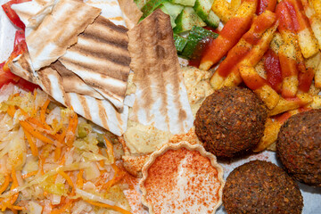 Middle Eastern or Arabic cuisine. Close-up of falafel, hummus, tabbouleh, pita bread and vegetables, top view