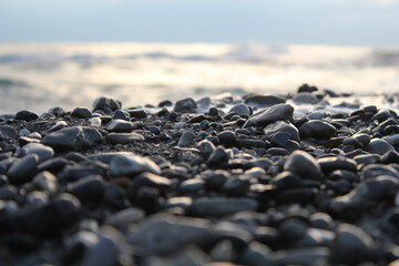 Wet pebbles on the beach, the sea in the background. Relaxation, solitude, meditation. Background for a motivational or philosophical text. Close-up photos, selective focus.