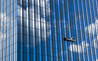 Tall skyscraper and professional high rise window cleaning service workers in a gondola © Joerg-alois/Wirestock