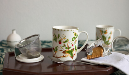 Cups of tea on a tray, with a cookie and a napkin