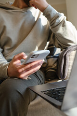 Man holds a phone in his hands and plays and he is happy with the result. A young man sits on the couch and has fun with a gadget, watch a sports match. Uses a mobile device app, sends text messages