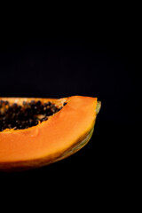 Half of fresh papaya laying down on black surface