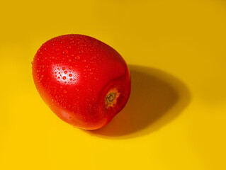 Fresh tomato on a yellow surface