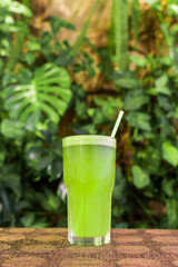 Delicious smoothie of natural vegetables and fruits on an unfocused background of leaves. Healthy fitness diet concept