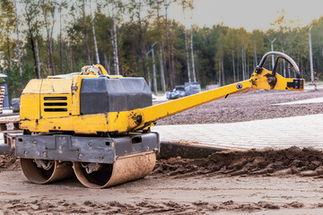 Manual compact asphalt roller for tamping soil at a construction site. Road works with the use of...
