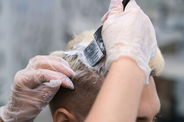 Hair dyeing for a young man in a hairdressing salon.