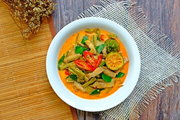 Authentic Thai red curry with pork belly and morning glory (Gaeng Tay Po) on wooden table. Thai food.