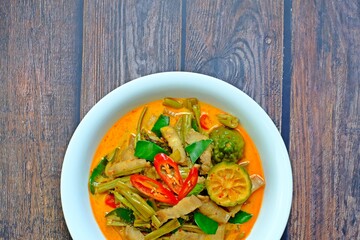 Authentic Thai red curry with pork belly and morning glory (Gaeng Tay Po) on wooden table. Thai food.