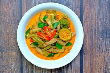 Authentic Thai red curry with pork belly and morning glory (Gaeng Tay Po) on wooden table. Thai food.