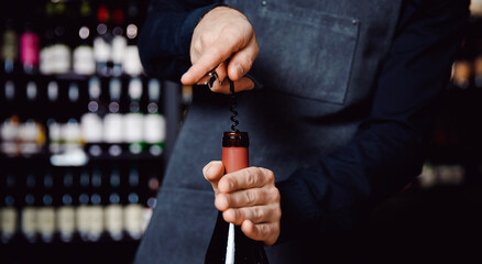 Sommelier opens cork of bottle of red wine with corkscrew, concept banner tasting