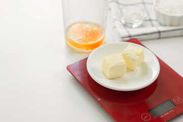 Step 2: Weighing butter on a kitchen scale. Step by step recipe for baking sweet plum pie. Ingredients set for cooking. Sweet pastries on white background. Culinary light background