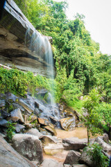 A small waterfall falls from the cliff.