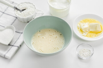 Step 3: Beaten eggs with sugar, butter are basis for dough. Step by step recipe for baking sweet plum pie. Ingredients set for cooking. Sweet pastries on white background. Culinary light background