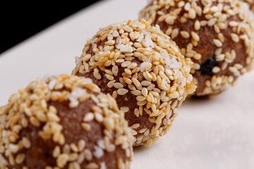 Beautiful candies with sesame seeds on a white plate on a black background