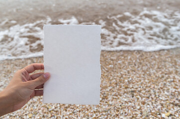 White blank paper sheet card mockup with copy space on sea sand background. Summer stationery mock-up scene. Top view minimal business brand, wedding invitation  template