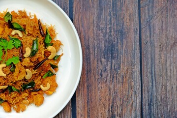 Thai sweet and sour crispy noodles (Mee Krob), crispy rice noodles in white plate on wooden table. Authentic Thai food.