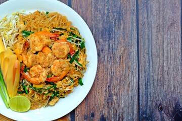 Fried rice noodle with shrimp (Pad Thai Goong Sod) in white plate on wooden table.