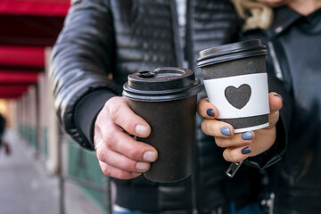 Morning coffee. Woman and man holds a disposable coffee cup with heard shape on glass