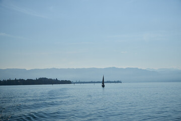 Der Bodensee mit Segelbooten und Bergen im Hintergrund