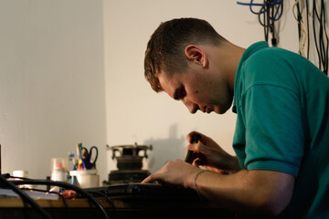 Young man, engineer soldering black laptop. Electronic renovation in repair service. Worker check damaged technician tool, computer. Professional
