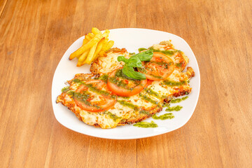 Argentinian veal schnitzel with melted mozzarella cheese, tomato slices, pesto sauce and side of...