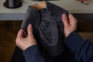Shoemaker checking quality of the seam of handmade shoes in workshop. Female hands holding craft leather shoe.
